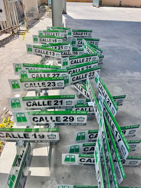 Stacked green and white street signs displaying Bogota calle numbers arranged in a construction area